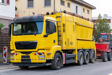 Suction excavator truck, with other machinery on a street construction site.