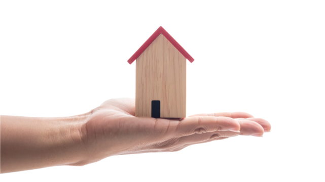 A hand holding a miniature wooden house with red roof. Showcasing concept of property ownership, housing and real estate