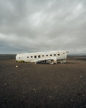View of the stark white shell of a crashed DC-3 contrasts against the vast, desolate black sand beach under a brooding sky, S&oacute;lheimasandur, Myrdalshreppur, Iceland.