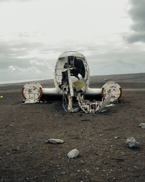 View of the weathered skeleton of a crashed DC-3 airplane rests forlornly on the stark, black sands under a cloudy sky, S&oacute;lheimasandur, Myrdalshreppur, Iceland.