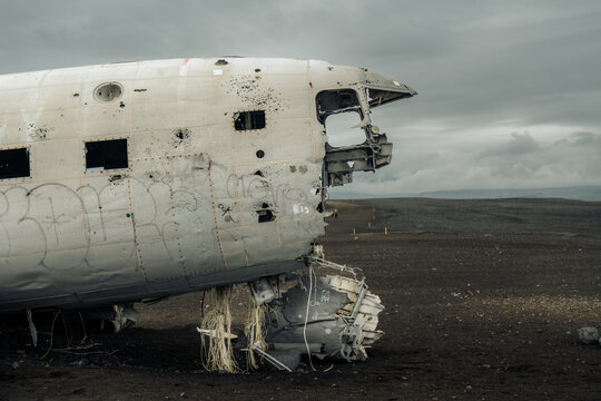 View of the skeletal remains of a weathered DC-3 plane, a ghostly relic against the stark, black volcanic sands under a somber sky, S&oacute;lheimasandur, Myrdalshreppur, Iceland.