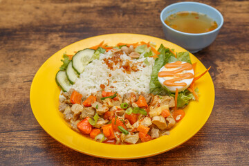 Ayam Curry – poulet mijoté aux épices malaisiennes, servi avec riz, présenté dans une assiette colorée sur table en bois. Cuisine malaisienne. 