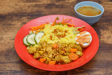 Curry Chicken – poulet mijoté aux épices, plat malaisien présenté dans une assiette colorée sur table en bois