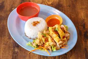 Nasi Lemak – Plat traditionnel malaisien avec poulet mariné frit, riz parfumé au lait de coco, œuf dur et sauce pimentée, présenté sur une assiette colorée sur table en bois. Cuisine malaisienne.