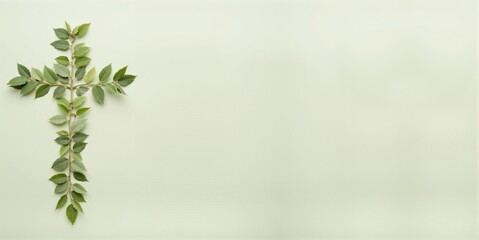 Obraz premium A symbolic cross made up of green leaves placed on a soft neutral background.