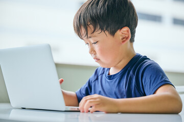ノートパソコンでオンライン学習をする小学生の男の子