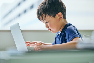 ノートパソコンでオンライン学習をする小学生の男の子