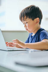 ノートパソコンでオンライン学習をする小学生の男の子