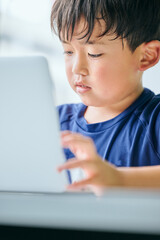 ノートパソコンでオンライン学習をする小学生の男の子