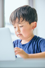 ノートパソコンでオンライン学習をする小学生の男の子
