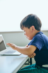 ノートパソコンでオンライン学習をする小学生の男の子