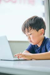 ノートパソコンでオンライン学習をする小学生の男の子
