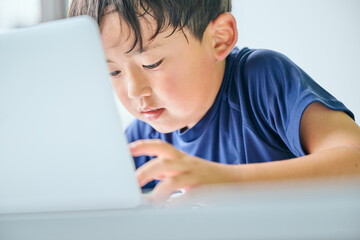 ノートパソコンでオンライン学習をする小学生の男の子
