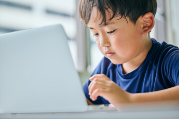 ノートパソコンでオンライン学習をする小学生の男の子