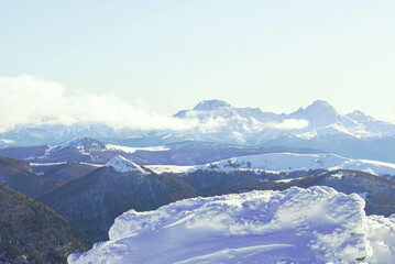 Layered ranges with snow-covered peaks visible through atmospheric haze and cloud formations. Winter mountains of Montenegro: view of Mount Komovi from Kolasin 1600 ski resort. Balkan alpine landscape