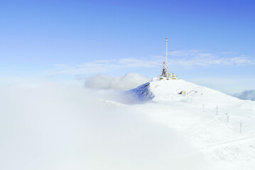 Mountain communication tower rising above dense cloud blanket at the top of Zekova Glava in Montenegro. Concept of winter atmospheric conditions, telecommunication facility, and highland installation.