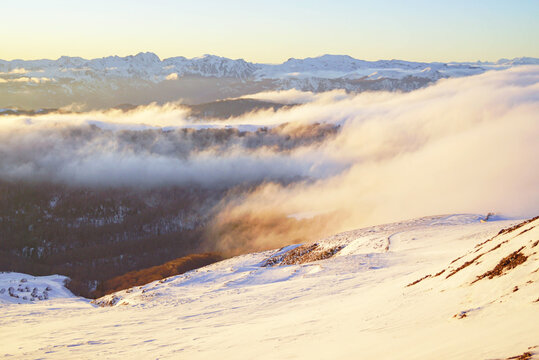 Scenic sunset at the Kolasin 1600 ski resort: a view of snow-capped mountains, fog and a dramatic ridge in the distance. Concepts of eco escape, sustainable tourism, and ski travel inspiration.