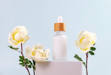 bottle of essential oil with a pipette and cream rose flowers on a white podium. The concept of skin care using natural cosmetics