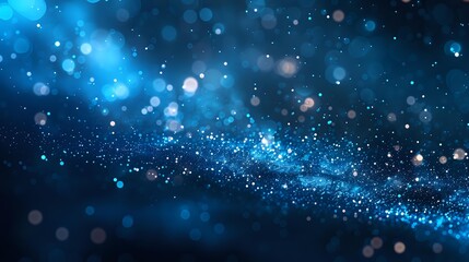 Magical blue bokeh lights and glowing particles floating in dark space create dreamy atmospheric background for festive designs and holiday projects.