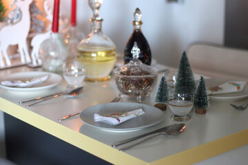 Table set for Christmas meal, with plates, wine, decorations and lit candles. Selective focus.