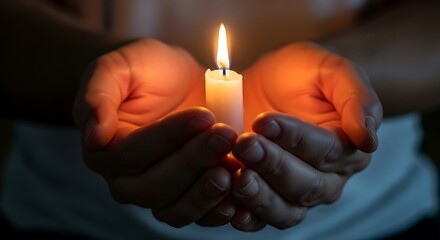Hands holding a candle flame in the darkness.