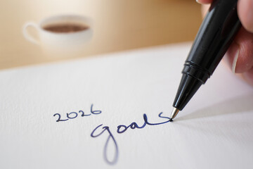 Fototapeta premium Writing Down 2026 Goals Black Pen on Paper With Coffee Mug