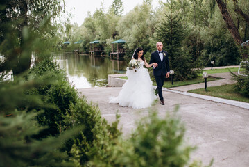 A black-haired bride in a white dress and a groom in a blue suit