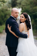A black-haired bride in a white dress and a groom in a blue suit