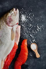 Sea trout and red caviar on black slate. Cooking process. Fresh fish with roe