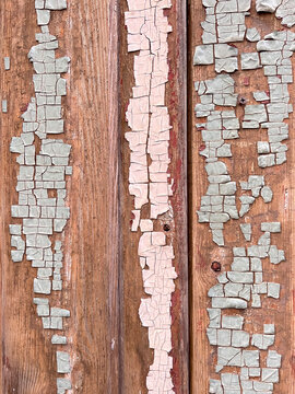 Macro texture of old wooden boards with peeling pink-beige paint. Weathered surface with delicate cracks and exposed wood. Vintage shabby background with natural tones and artistic decay