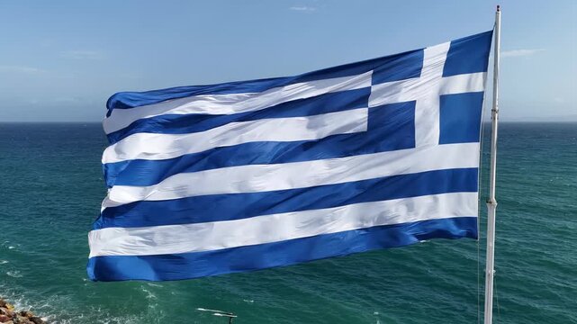 Large Greek flag waving proudly on a tall pole under the clear blue sky. Symbol of freedom, pride, and national identity of Greece, captured in crisp 4K ultra-high definition.
