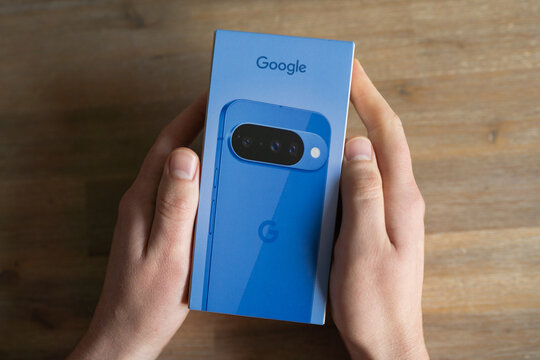 Haarlem, Netherlands,October, 24, 2025:Hands holding a blue smartphone google box with camera features displayed on the front, showcasing modern technology 