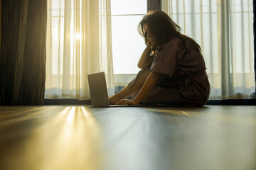 Concentrated businesswoman using laptop while sitting on floor with serene morning light filters through sheer curtains, large windows and a warm atmosphere. Enjoy carefree rest and optimistic mood