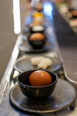 Egg in Black Bowl on Conveyor Belt at Shabu-Shabu Restaurant