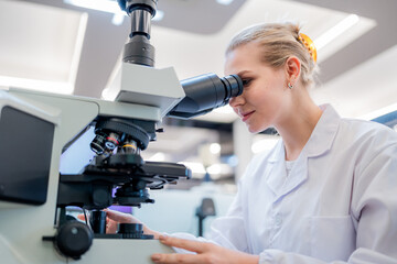 Scientist examines slide using microscope in modern laboratory setting during bright daytime