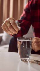 Hand pouring white medicine powder from sachet into glass of water. Concept of pharmacy product usage, health education, and wellness instruction.