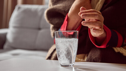 Elderly woman watching effervescent tablet dissolve in glass of water. Concept of pharmacy...