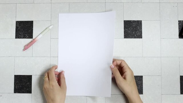 Person holding white empty paper A4 on tiles backdrop