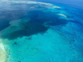 Aerial view of the turquoise sea embracing shallow reefs, where the sun paints shifting patterns on the seabed, Progreso, Yucatan, Mexico.