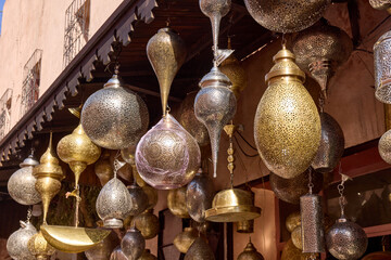 Numerous metal Moroccan lanterns hang from a building's awning. These traditional lanterns are...