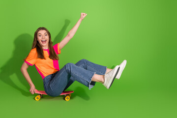 Young girl on a pink skateboard shows joy and style in a bright green background celebrating fun...