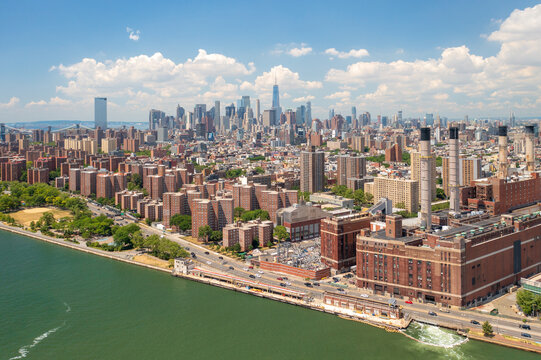 Aerial view of Con Ed Power station and the Manhattan skyline shimmer under a bright sky, where modern architecture meets the tranquil East River, New York, New York, United States.