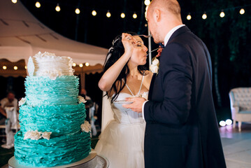 newlyweds happily cut, laugh and taste the wedding cake