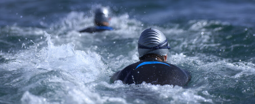 Open water swimmers in sleek wetsuits gracefully gliding through the vast sea.