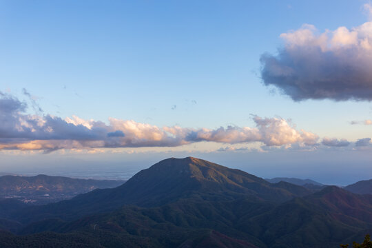 View of the sun kissing the mountain peaks, casting shadows across the landscape under a vast, cloud-strewn sky, Pizzo San Michele, Campania, Italy.