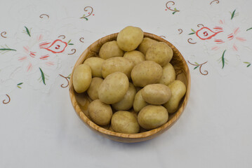 Cuenco de madera lleno de patatas sobre un mantel bordado