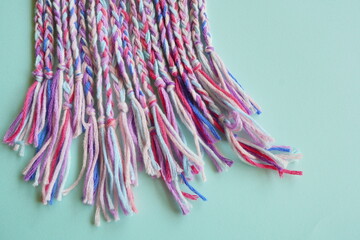 カラフルな糸で作られたミサンガが並ぶ、手作りの温かみを感じる写真。パステル調の配色が可愛らしく、ハンドメイド、クラフト、友情、プレゼントのイメージにも最適な素材。