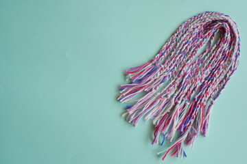 水色の背景に並べられた手作りのミサンガ。空間に余白をとった構図がデザイン向けで、広告やテキストスペース用素材にも使いやすい、明るく優しい雰囲気の写真。