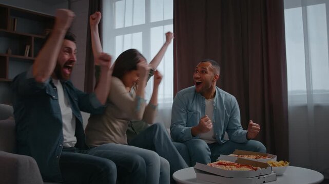 Group fans multiracial four friends watch television celebrating win sport game championship match supporting football team at home party buddies guys girls raising hands in excitement victory indoors