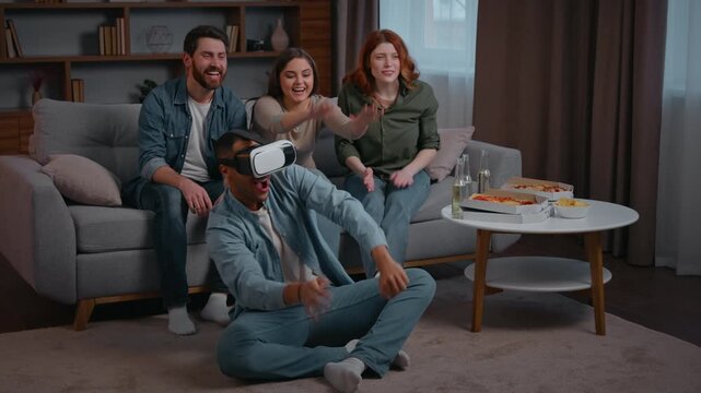 Four diversity ethnic friends at home party African american Latina man playing VR battle buddies men women saupporting applauding motivating virtual reality technology AR headset metaverse game using
